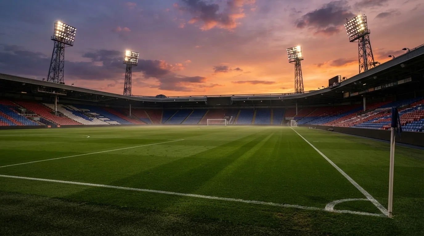 Un estadio de fútbol vacío con torres de iluminación al atardecer