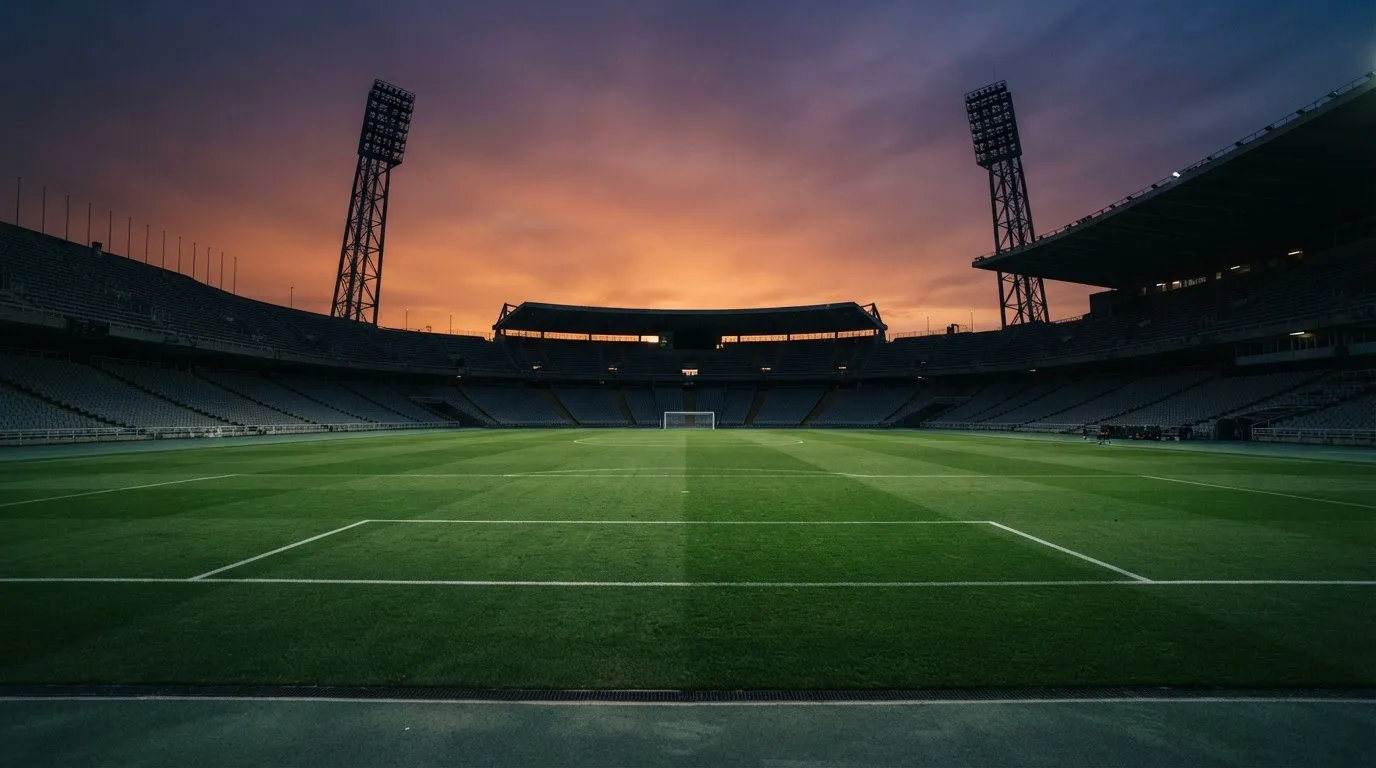 Un estadio de fútbol vacío con torres de iluminación al atardecer