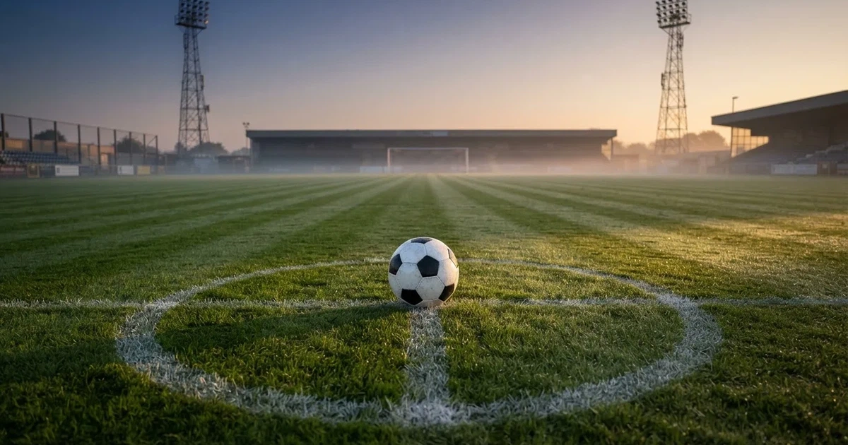 Un balón en el punto central de un campo de césped a la luz de la mañana