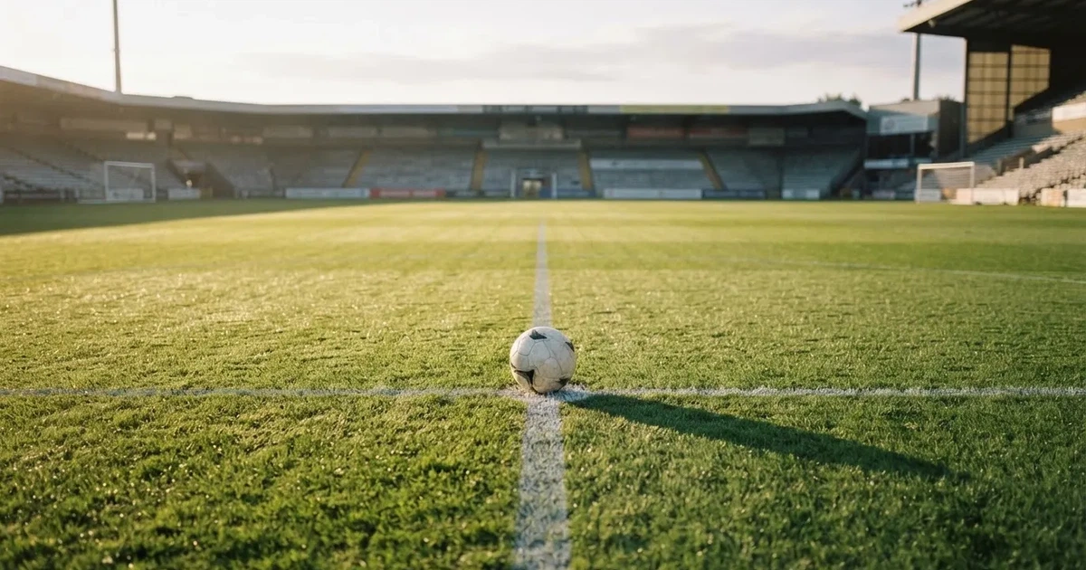 Un balón en el punto central de un campo de césped a la luz de la mañana