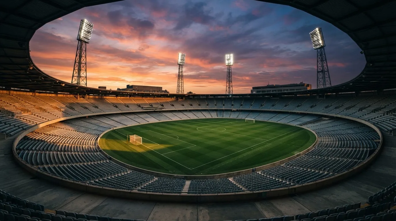Un estadio de fútbol vacío con torres de iluminación al atardecer