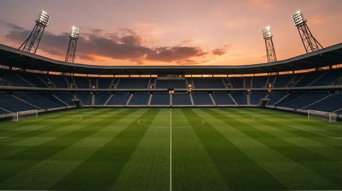 Un estadio de fútbol vacío con torres de iluminación al atardecer