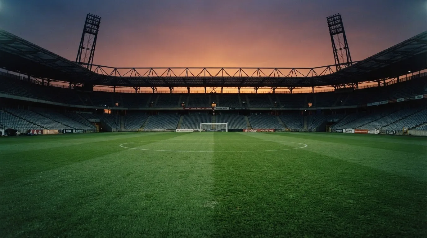 Un estadio de fútbol vacío con torres de iluminación al atardecer
