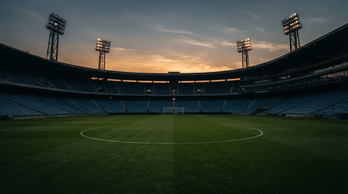 Un estadio de fútbol vacío con torres de iluminación al atardecer