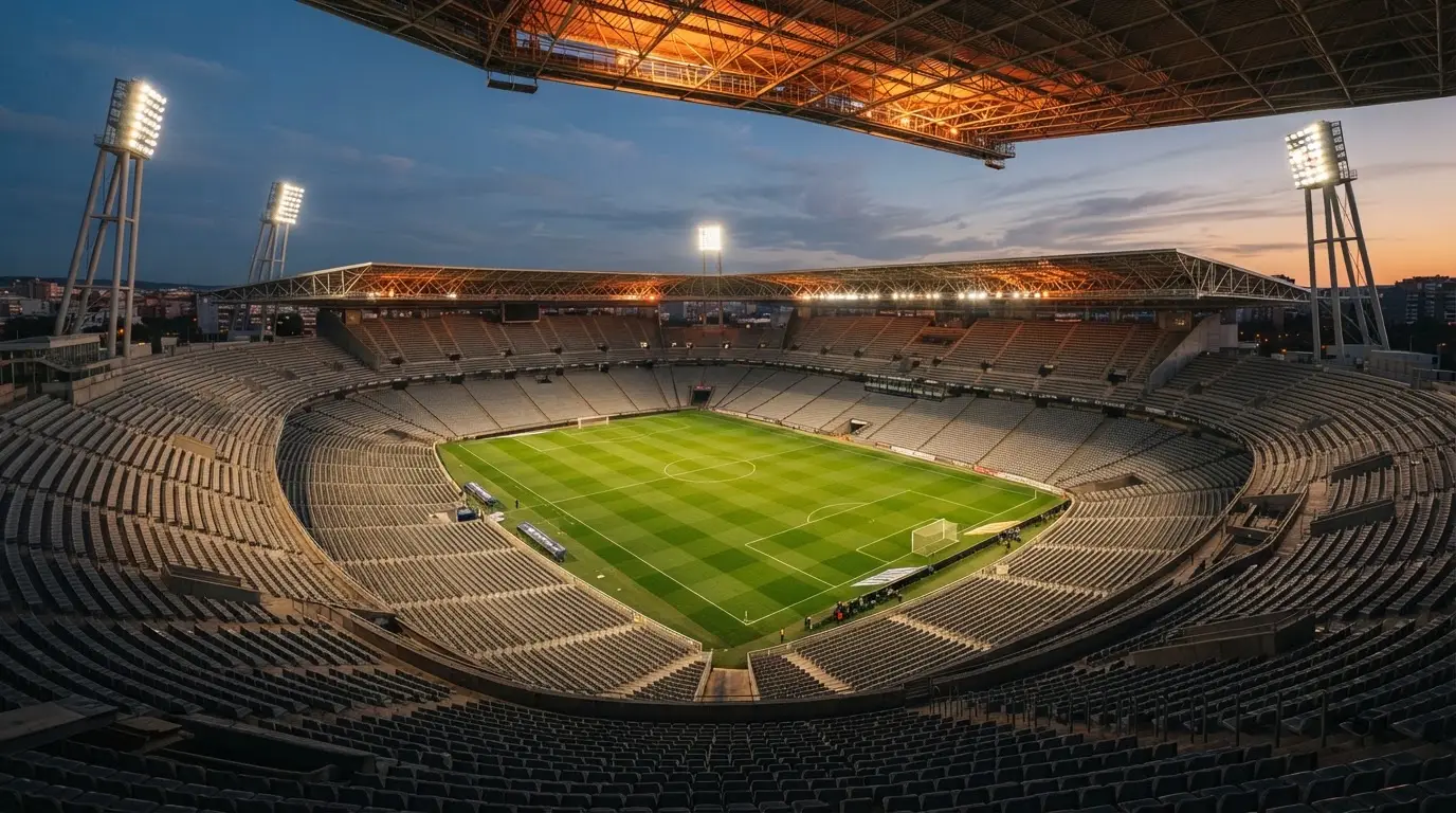 Un estadio de fútbol vacío con torres de iluminación al atardecer