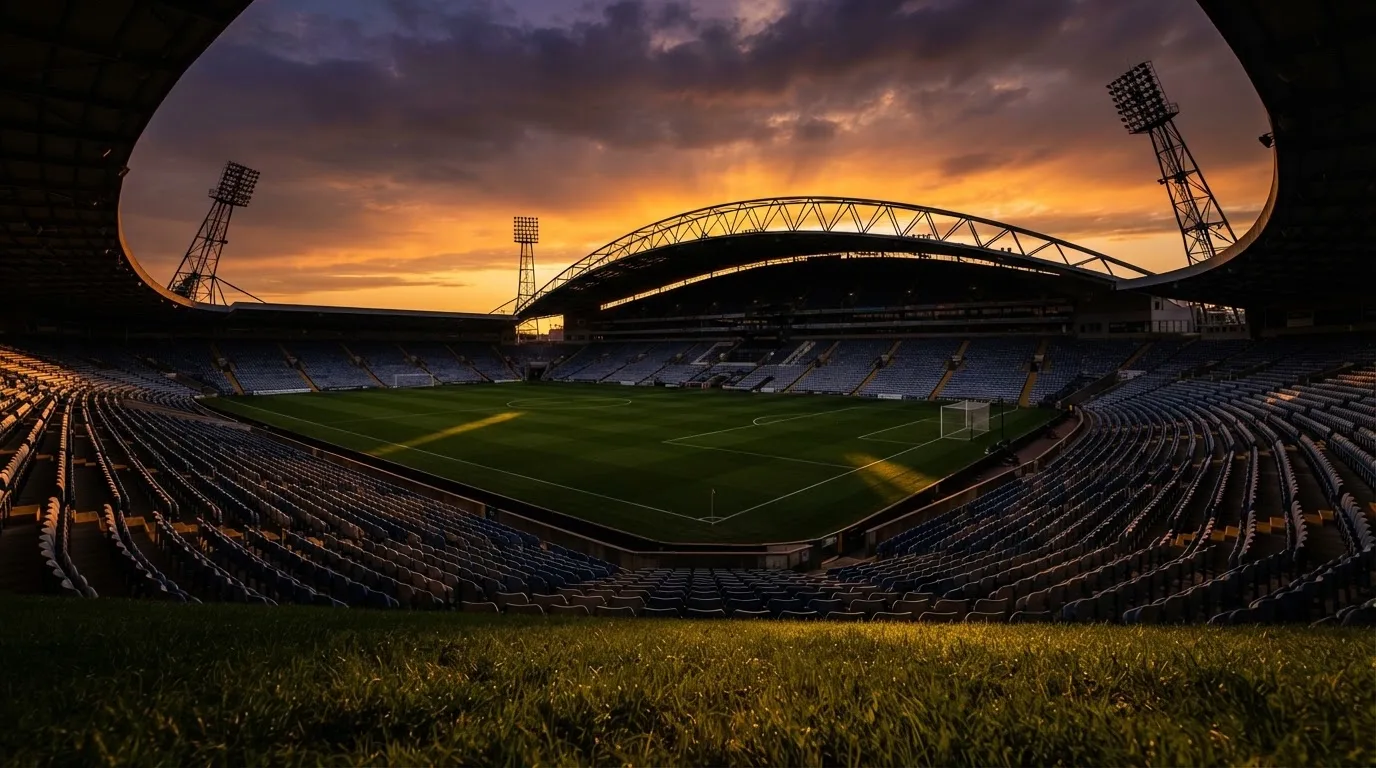 Un estadio de fútbol vacío con torres de iluminación al atardecer