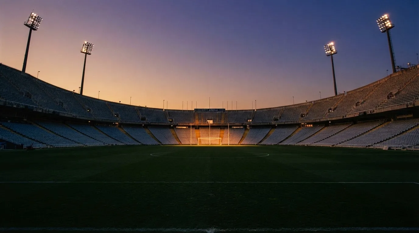 Un estadio de fútbol vacío con torres de iluminación al atardecer