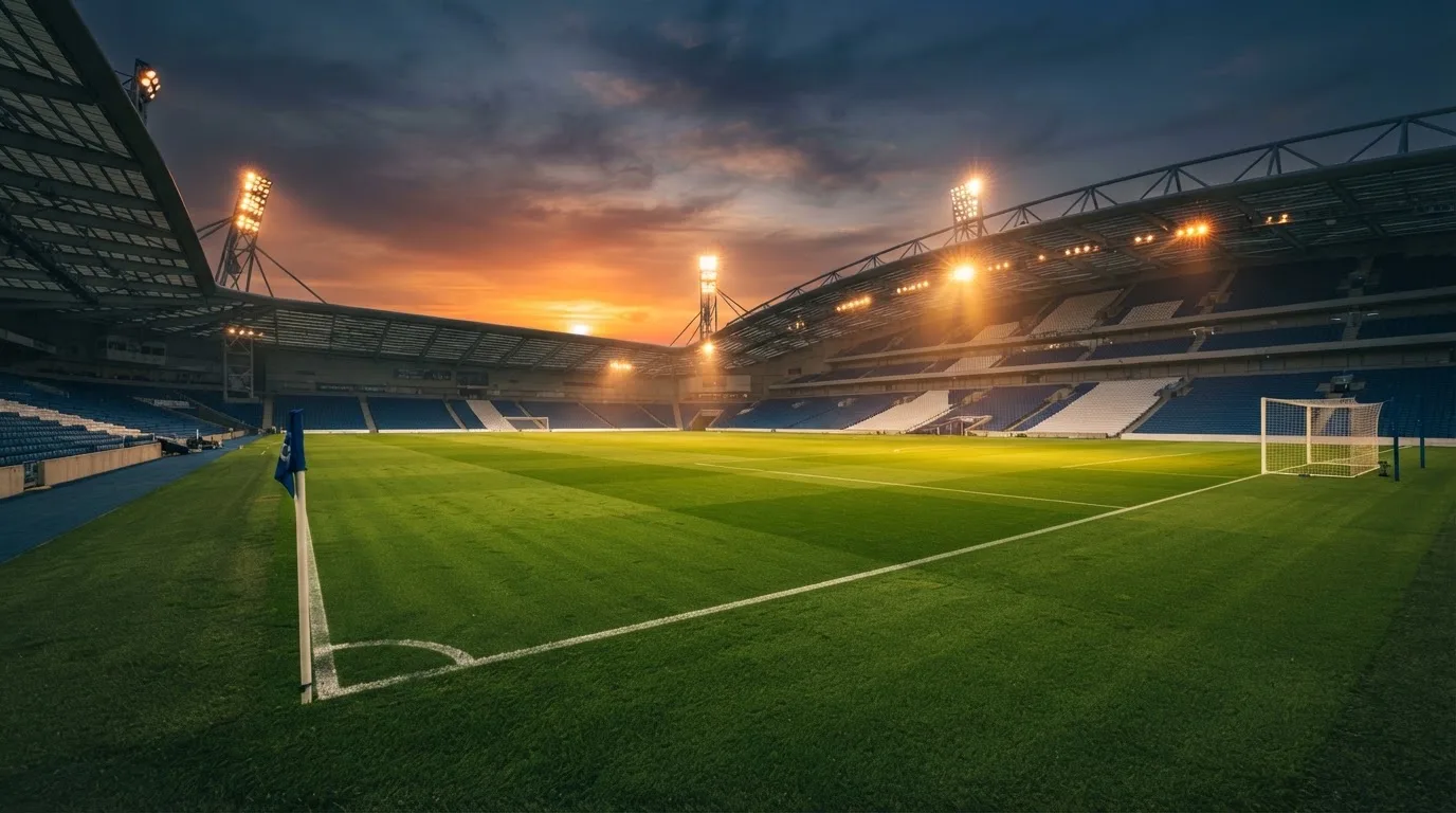 Un estadio de fútbol vacío con torres de iluminación al atardecer