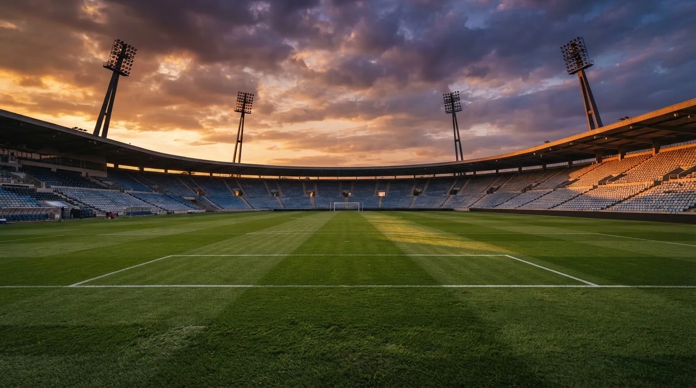 Un estadio de fútbol vacío con torres de iluminación al atardecer